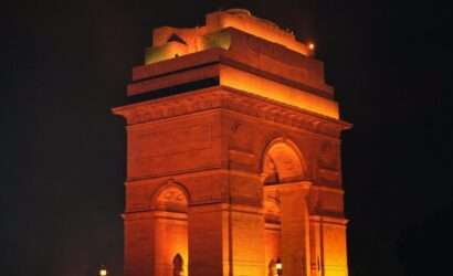 "India Gate illuminated at night with orange and yellow lights"