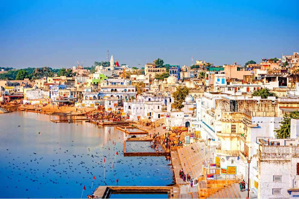 "Devotees praying and taking a dip in the holy waters of Pushkar Kund surrounded by ancient temples."