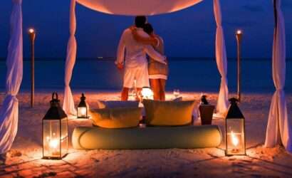 Two couples enjoying a romantic evening on a decorated tent at the beach.