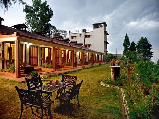 "A stunning view of a resort in Ranikhet, surrounded by lush greenery and beautiful mountains in the background."