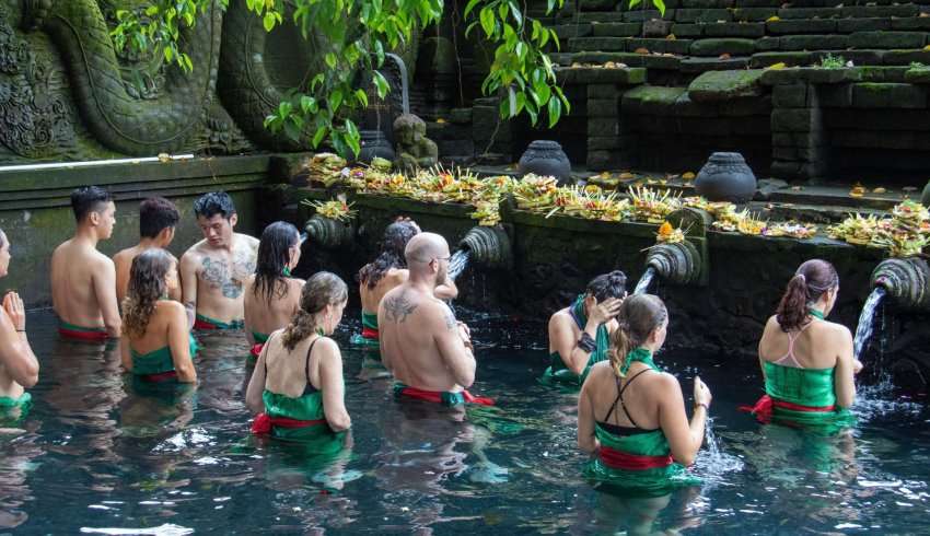 "Tourists bathing in the holy water pools of Pura Tirta Empul, a Hindu Balinese water temple"