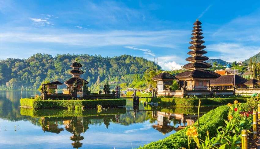 "Ulun Danu Beratan Temple, a majestic water temple in Bali surrounded by lush greenery and mountains, with a reflection of the temple on the lake water."