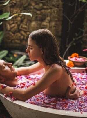 "Romantic couple enjoying a bath in a tub filled with rose petals"