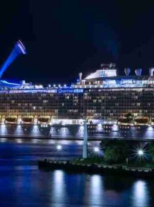 "Big cruise ship illuminated with blue lights in the night sky, Dubai"