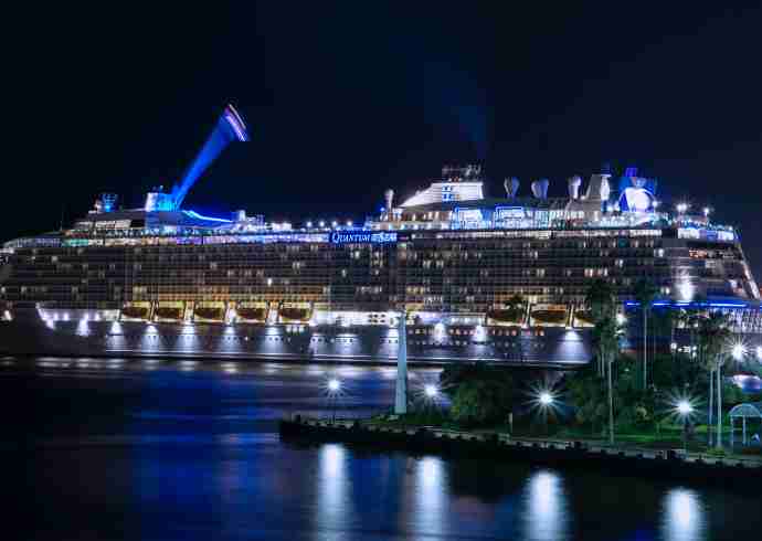 "Big cruise ship illuminated with blue lights in the night sky, Dubai"