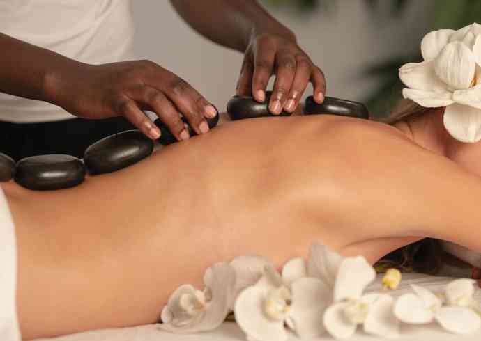 "woman receiving hot stone massage on her back in traditional Balinese Ayurvedic spa"