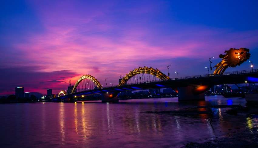 "Dragon Bridge over the Han River in Da Nang, Vietnam, with colorful lights and dragon sculptures, at night"