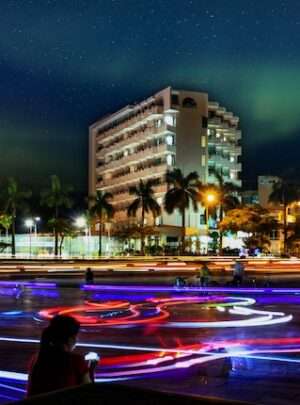 "woman sitting outside luxury hotel, enjoying city view at night"