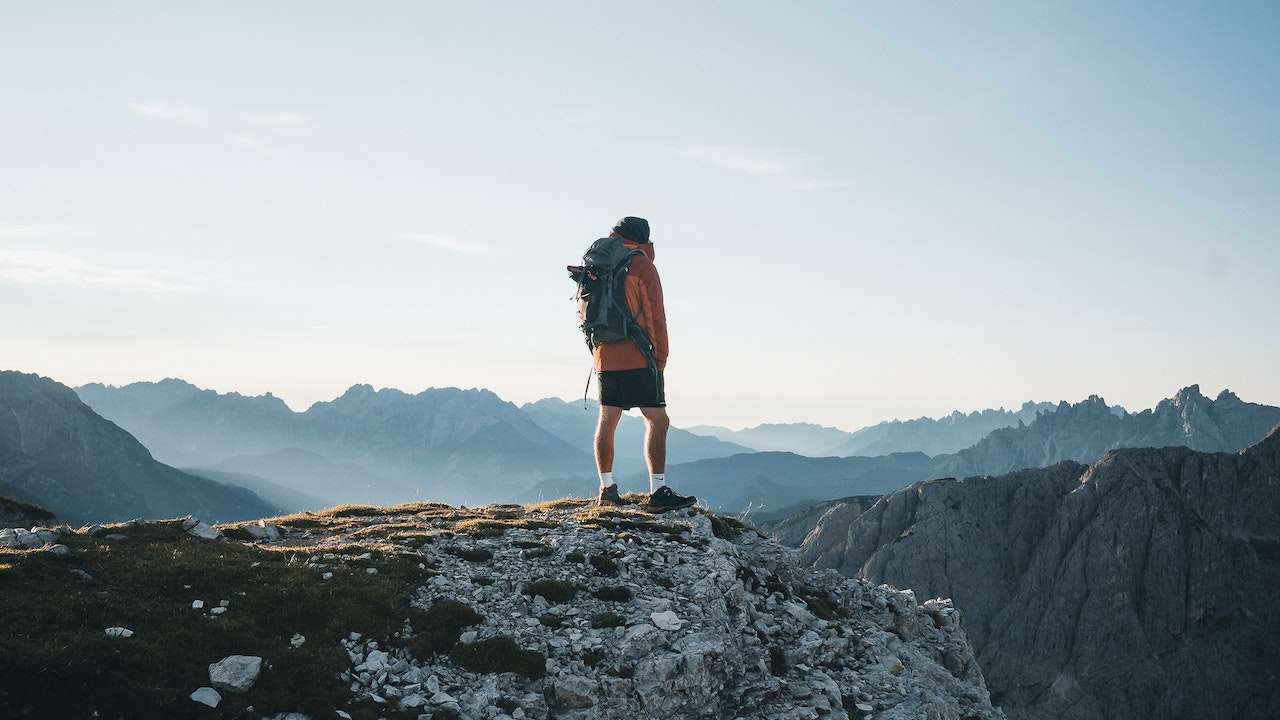 Tourist standing on a hill with a backpack, enjoying the scenic view