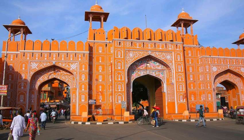 "View of Ajmeri Gate Monument in Jaipur, with ornate arches and intricate stonework, against a blue sky background."