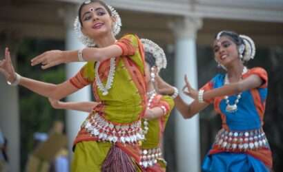 "South Indian girls in traditional outfits dancing with musical instruments for cultural performance"