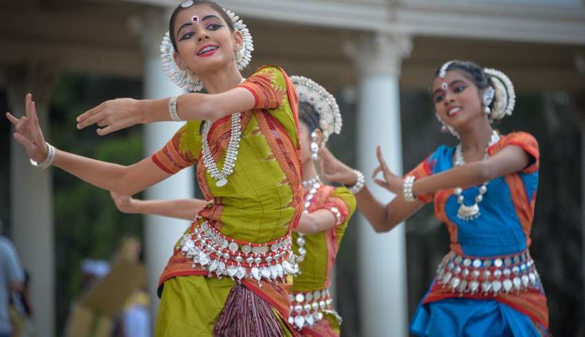 "South Indian girls in traditional outfits dancing with musical instruments for cultural performance"