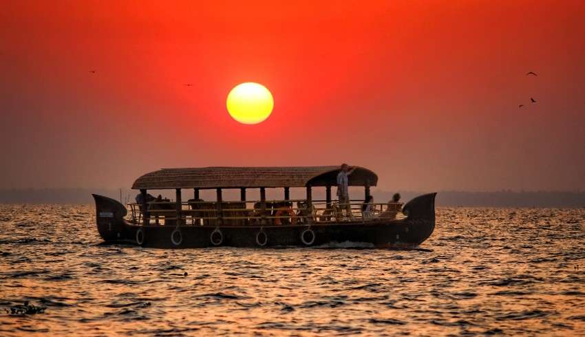 "Boat sailing in the backwaters of Kerala with an orange sunset in the background - South India"