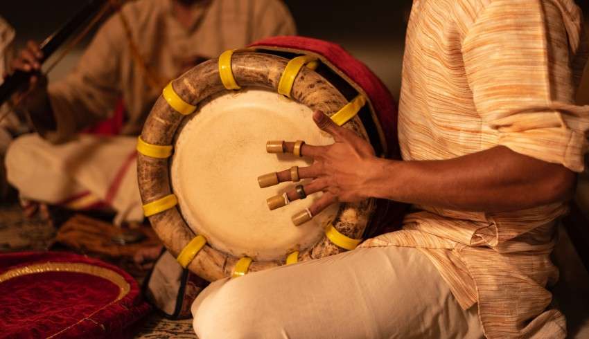 "A man playing a traditional Indian dholak drum during a cultural event in South India"