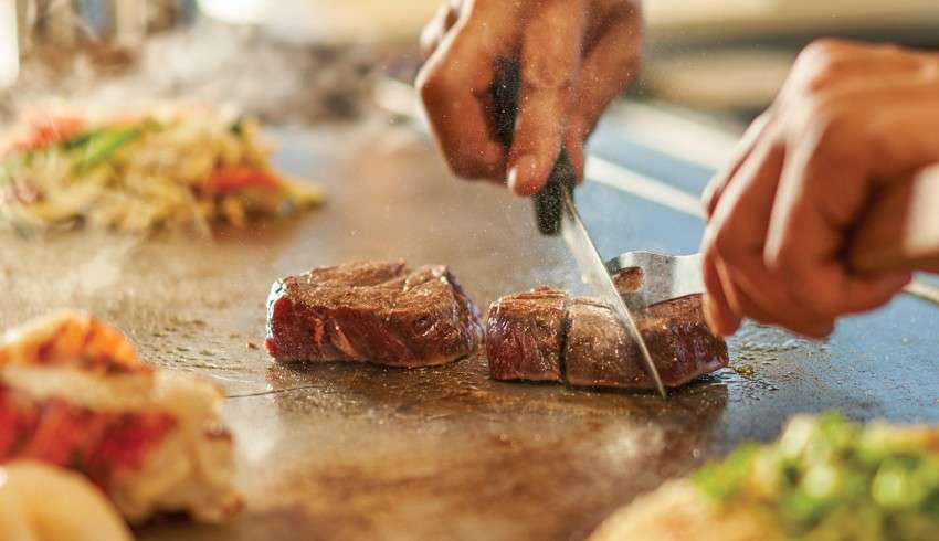 "Chef cutting pieces of meat in a cruise ship kitchen"