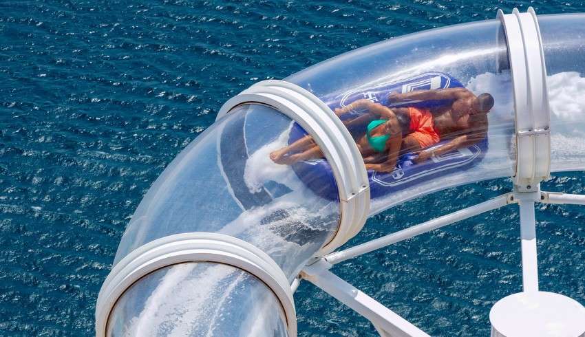 A couple sliding down a water slide on a cruise ship.