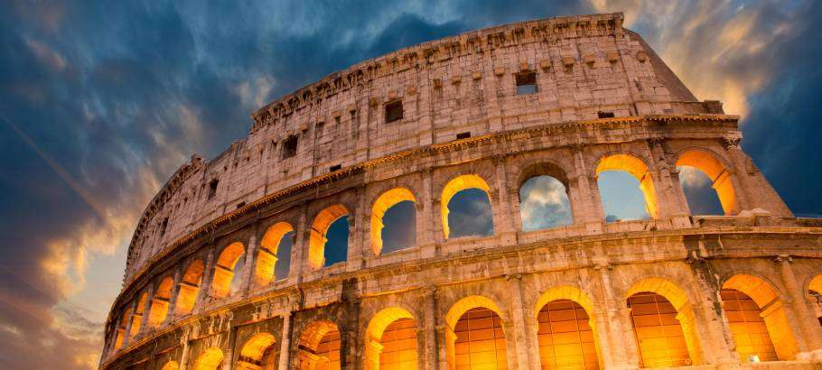 The Colosseum in Rome, Italy, is a grand amphitheater with rows of arches, towering over the surrounding city.