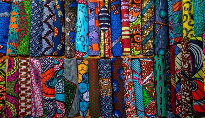 "Colorful African dresses displayed on a street shop wall"