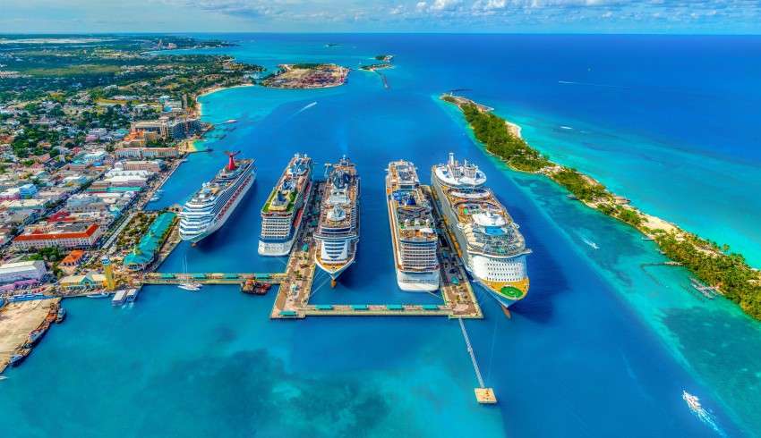 "Five Royal Caribbean cruises docked side by side at a port, ready for passengers to board."