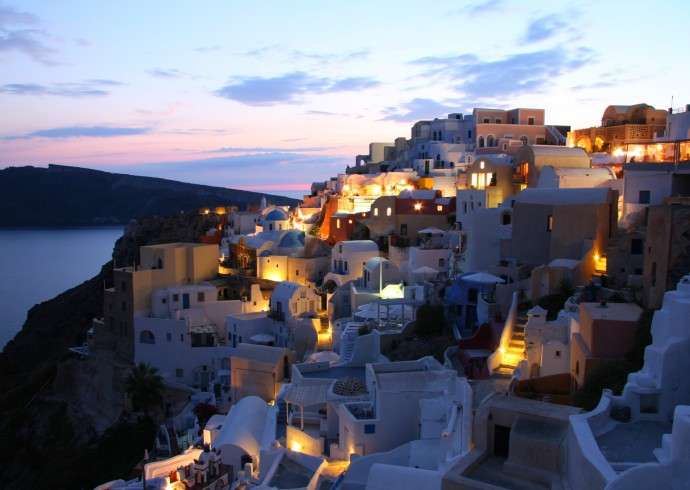 "blue domes and a white building glowing in the warm evening light of Santorini, Greece"