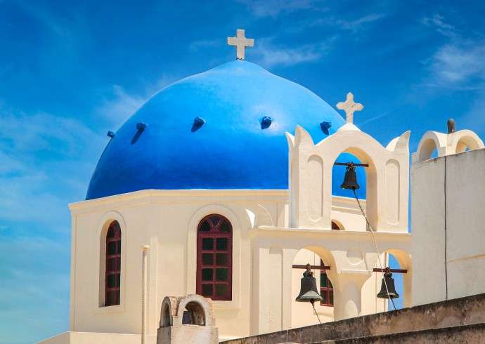 "Blue domes with white buildings in Santorini, Greece against a clear blue sky"