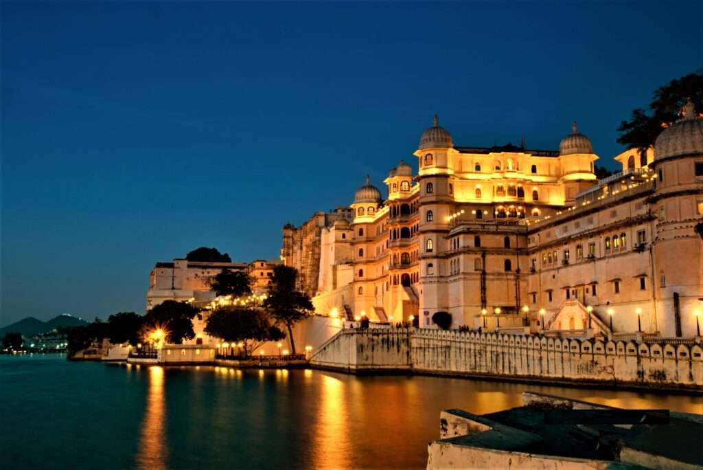 "Scenic view of Lake Pichola in Udaipur city, Rajasthan, India with boats floating in the water and the Aravalli Mountains in the background"