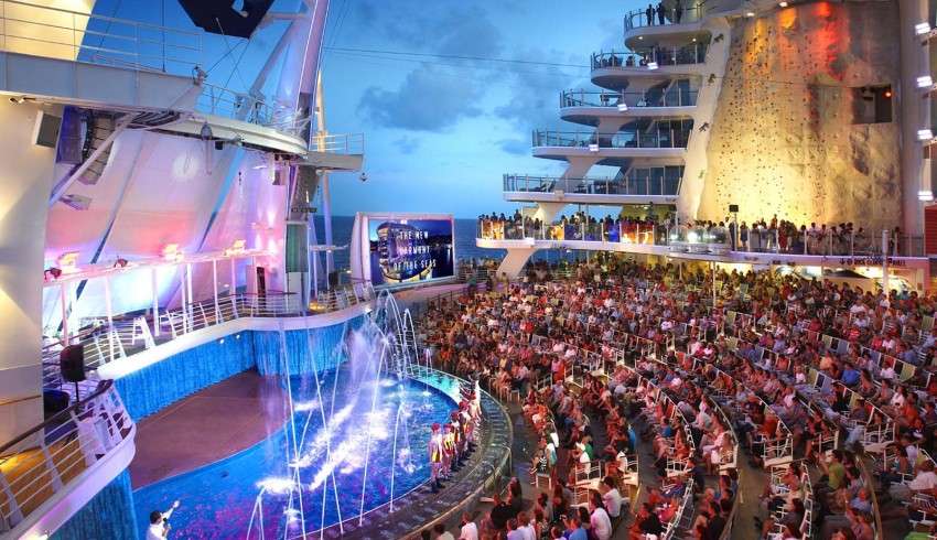 A person sitting in the audience watching a colorful and vibrant Aqua Theater Show on a Royal Caribbean cruise ship.