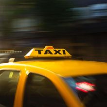 A yellow luxurious taxi passing through the city streets, offering transportation for tourists."